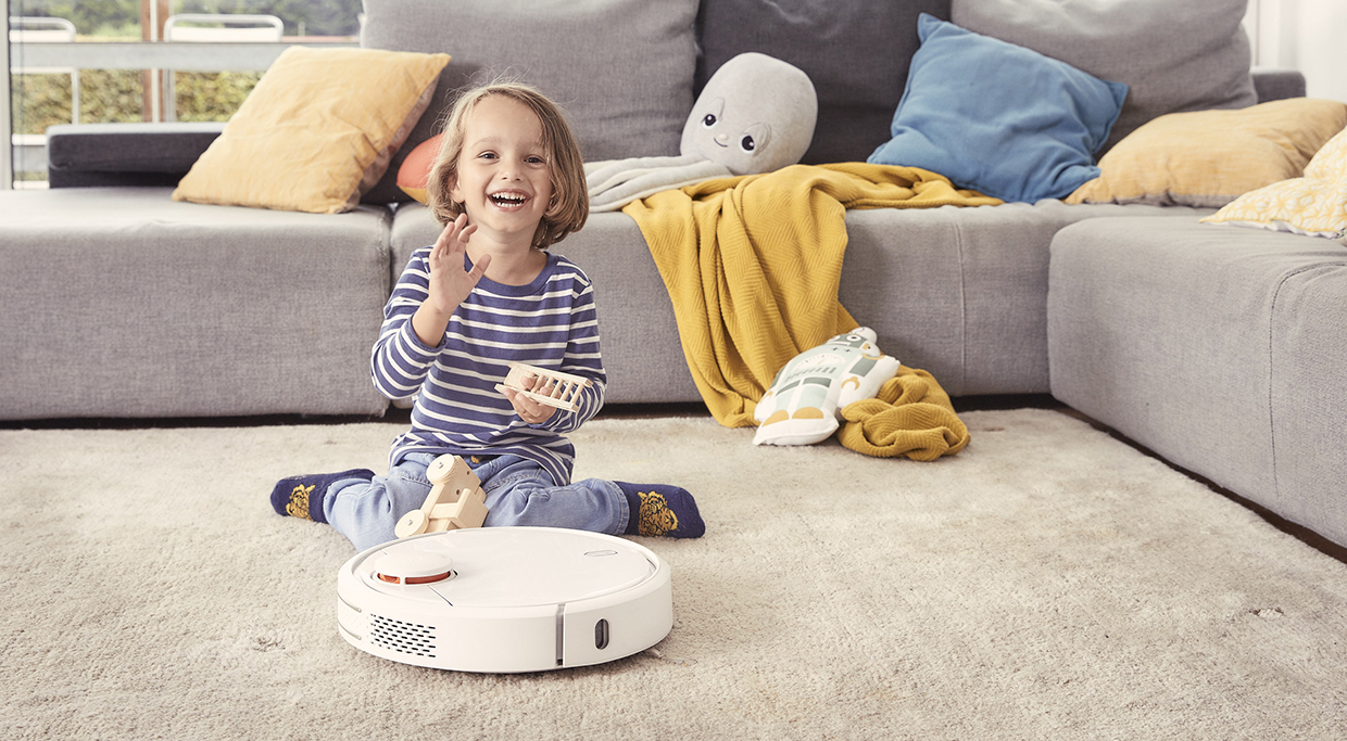 Spielendes Kind mit Staubsaugerroboter PRÄG Stromtarife spielendes Kind